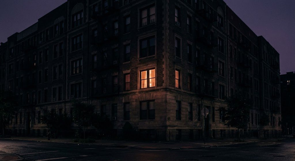A single warm-lit window at night — a sense of space and stillness